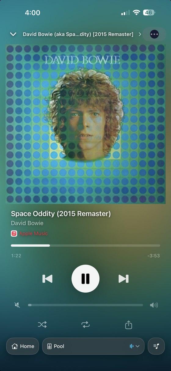 Now Playing on iPhone: full-screen album art with the background tinted to match